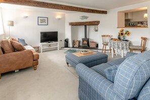 Ein Wohnzimmer mit Fernseher, Sofa, Hocker und Kamin.