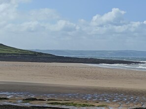 A beach with a rocky shoreline and distant hills. - 2 Bed in Swimbridge (oc-p44771) (Swimbridge)