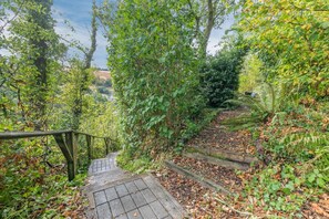 A wooden staircase surrounded by dense foliage, leading to a higher elevation. - 2 Bed in Swimbridge (oc-p44771) (Swimbridge)