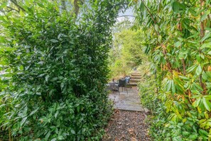 Ein Gartenweg mit Sitzgelegenheit und einer Steinmauer.