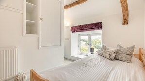 A bedroom with a bed, a window with a view, a radiator, and a wardrobe. - 2 Bed in Swimbridge (oc-p44771) (Swimbridge)