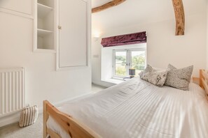 Ein Schlafzimmer mit Bett, Fenster mit Blick, Heizkörper und Kleiderschrank.