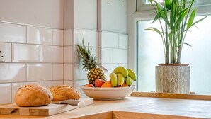 Eine Küchenarbeitsplatte mit Schneidebrett, Obstschüssel und Brotlaib.