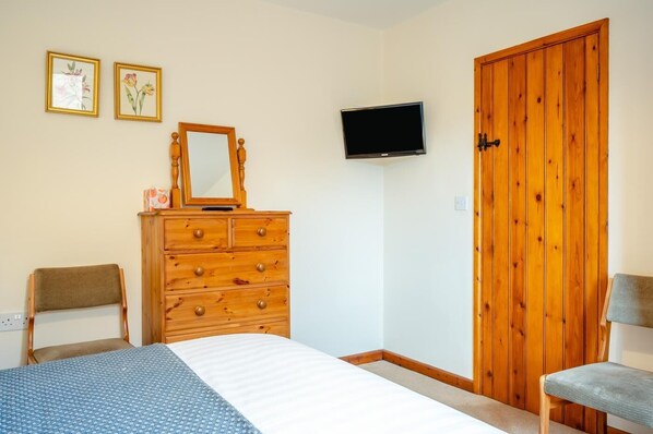 Ein Schlafzimmer mit einem Bett, einem Holzschrank, einem Fernseher und einem Kleiderschrank.
