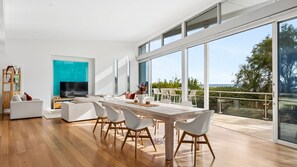 Ein modernes Wohnzimmer mit Essbereich, großen Fenstern und Blick ins Freie.