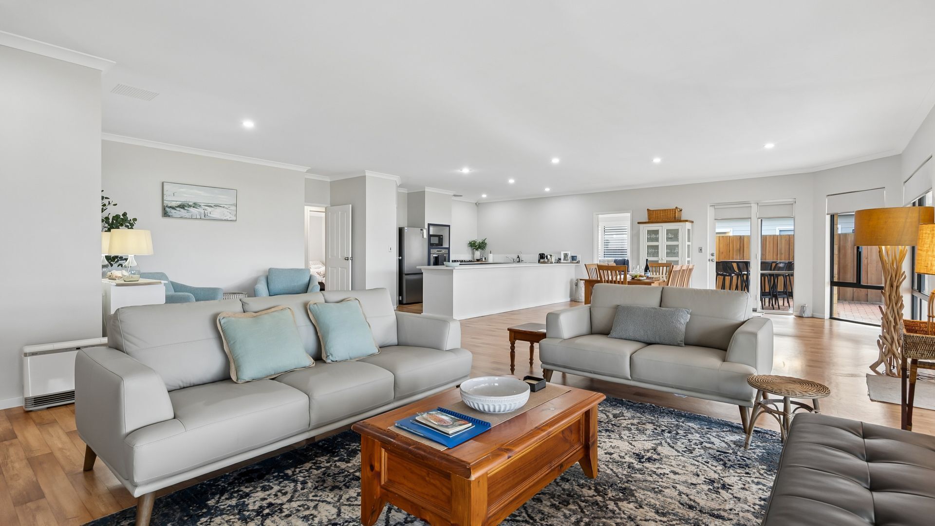 A modern living room with a sofa, coffee table, and a dining area in the background.