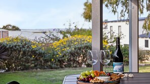A table with a bottle of wine, two glasses, and a cheese board with fruits and nuts. - Augusta Views Family Retreat (Augusta)