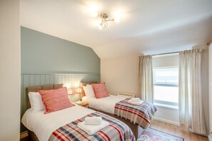 A hotel room with two beds, a window with curtains, and a ceiling light fixture. - 2 Bed in Penmachno (oc-y44743) (Penmachno)