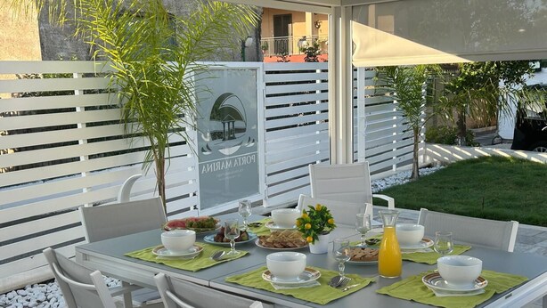 An outdoor dining area with a table set for four, surrounded by white chairs and a glass table. - Beautiful 4-bedroom resort with AC in tranquil Pompei (POMPEI)