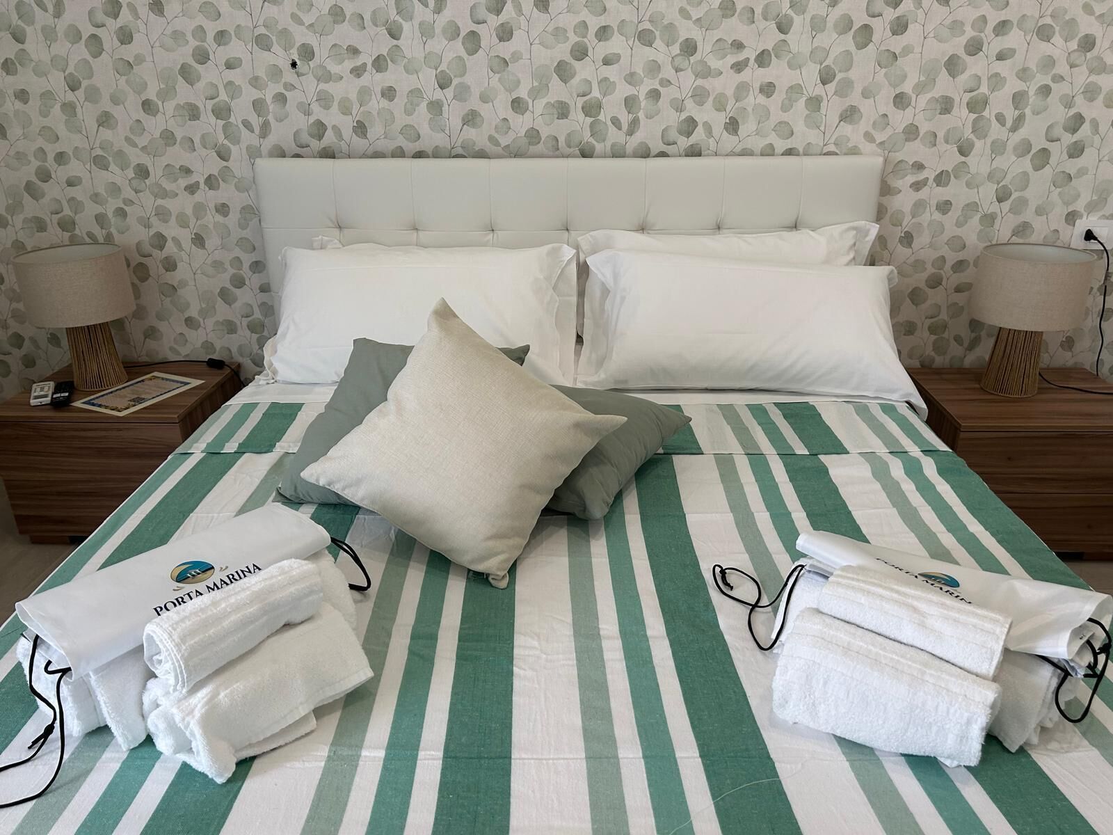 Ein Hotelzimmer mit einem Bett, Kissen, einer gestreiften Bettdecke und Handtüchern.