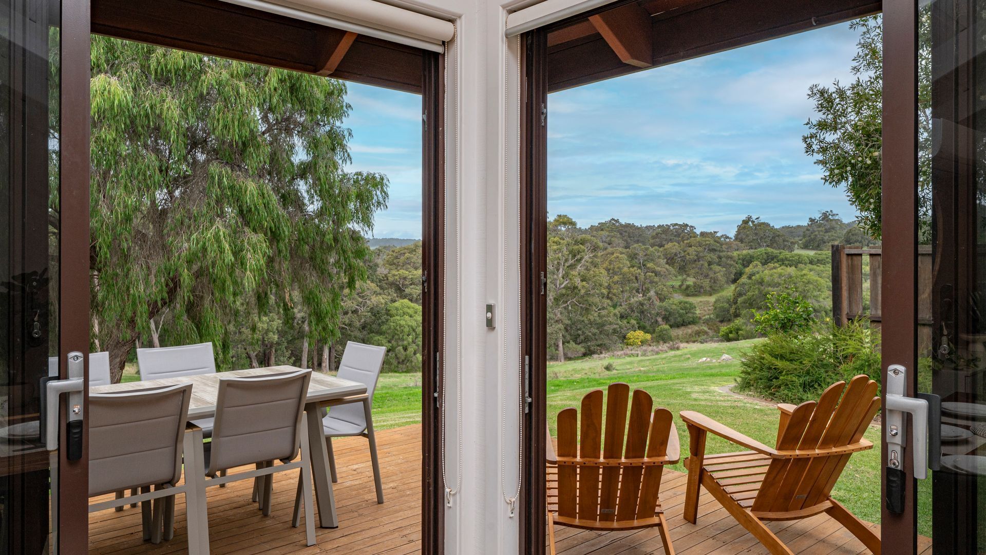 A deck with a table and chairs, overlooking a natural landscape.