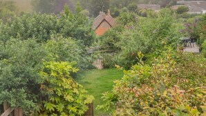 A garden with a house, surrounded by dense foliage and a clear view of the sky. - 2 Bed in Eype (oc-l42804) (Eype)