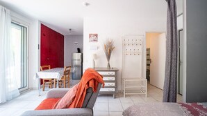 A modern living room with a sofa, a dining table, and a kitchen area in the background. - L'Écrin des Thermes - Proche des thermes (Amélie-les-Bains-Palalda)