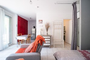 Ein modernes Wohnzimmer mit einer Couch, einem Esstisch und einer Küchenzeile im Hintergrund.