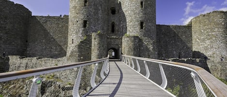 A stone castle with a wooden walkway leading to a central archway.