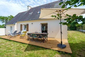 A house with a wooden deck, a table with chairs, and a large umbrella. - L'Escapade Bretonne - À 2 km de la plage (Fouesnant)