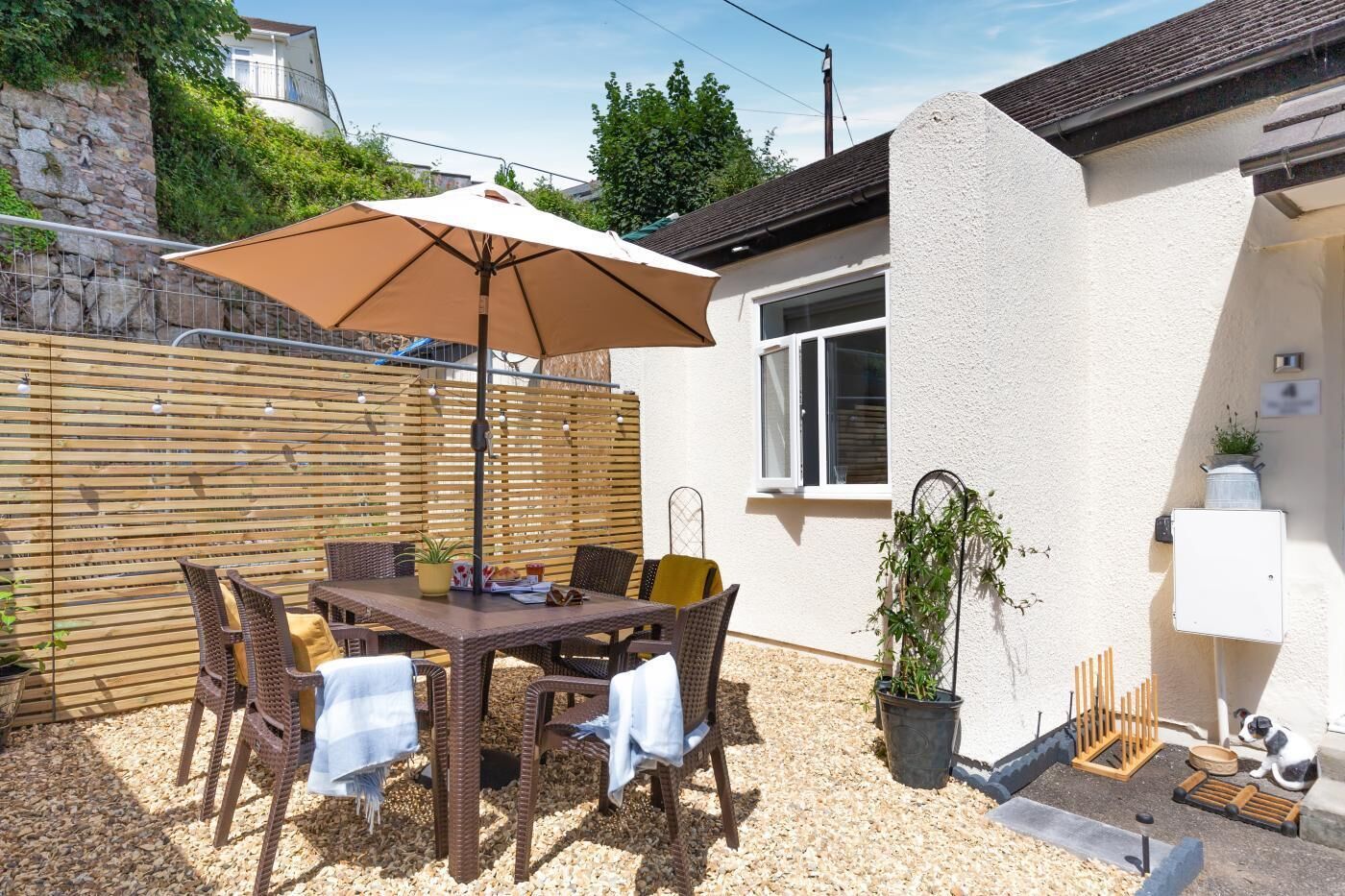 Eine Terrasse mit Tisch, Stühlen und Sonnenschirm.