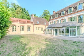 Un bâtiment à la façade en briques, doté de grandes fenêtres et d’un espace extérieur abrité.