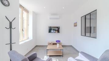 A modern living room with a sofa, a coffee table, a TV, and a coat rack.