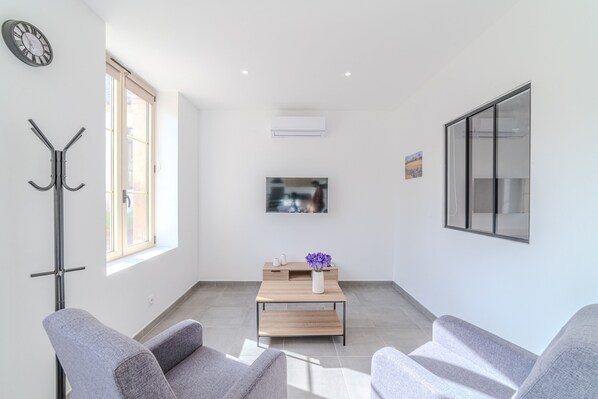 Un salon moderne comprenant un canapé, une table basse, un téléviseur et un porte-manteau.