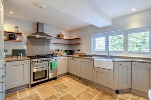 A modern kitchen with a gas stove, oven, and microwave, with a window providing natural light.
