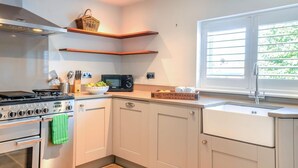 A kitchen with a stove, microwave, and a window with blinds.