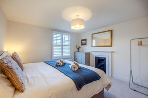 A bedroom with a bed, a dresser, a mirror, a fireplace, and a window with blinds. - 3 Bed in Forest Row (oc-h43282) (Forest Row)