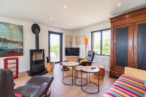 Ein modernes Wohnzimmer mit Kamin, einer Couch, einem Fernseher und einem großen Fenster.