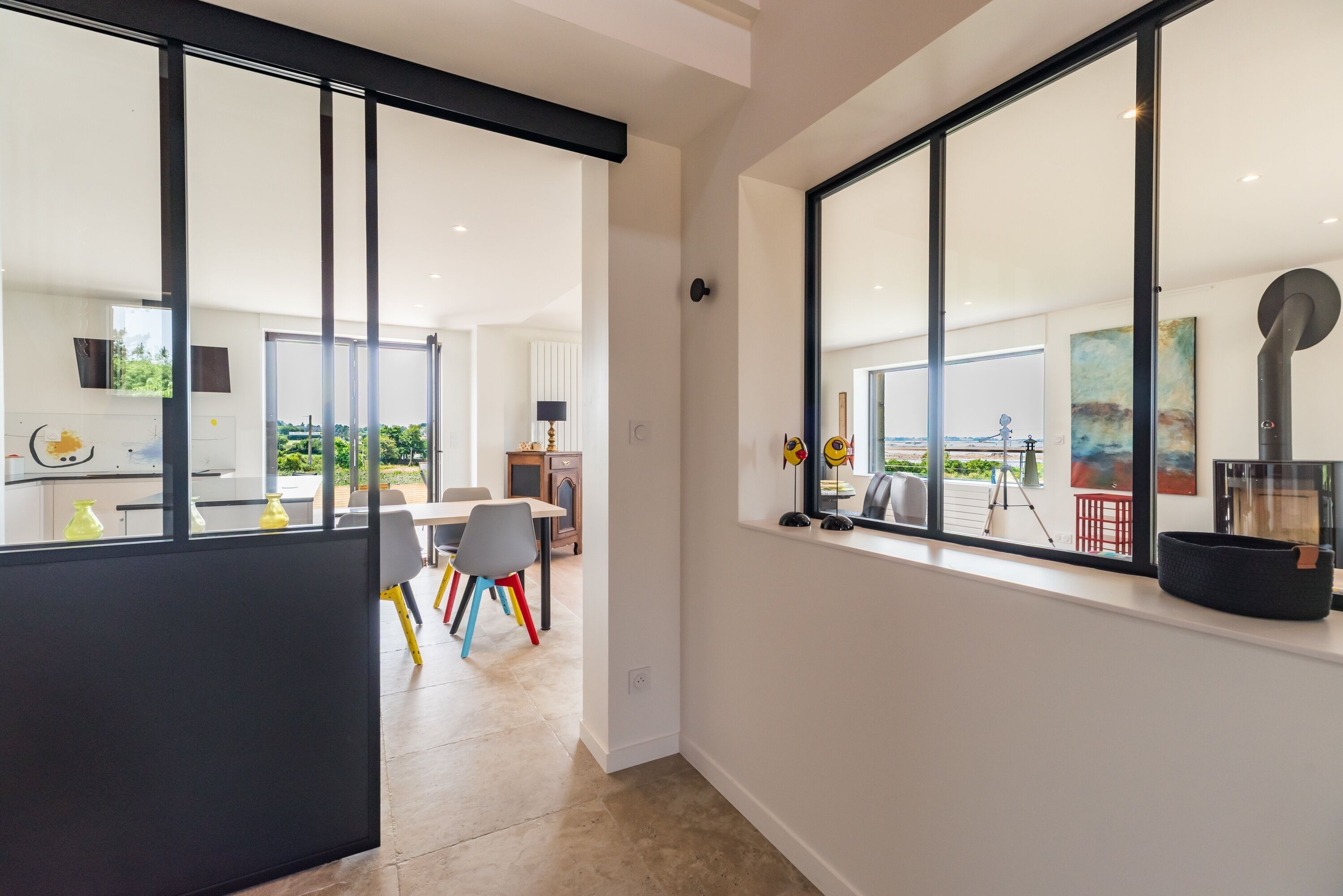 A modern interior with large windows, a dining area, and a view of the outdoors.