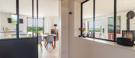 A modern interior with large windows, a dining area, and a view of the outdoors.