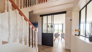 Ein modernes Interieur mit einer Treppe, einer Essecke mit Stühlen und einem großen Fenster.