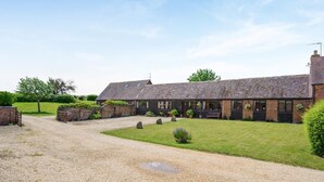 A two-story building with a gravel driveway and a grassy lawn. - 2 Bed in Stratford -upon- Avon (oc-cc009) (Welford-on-Avon)