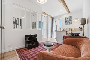Ein Wohnzimmer mit einer Couch, einem Fernseher, einem Couchtisch und einem Teppich.