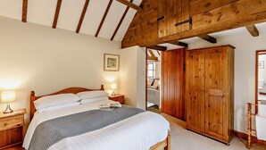 Un dormitorio con cama de madera, lámparas de noche, un armario y un cuadro en la pared.