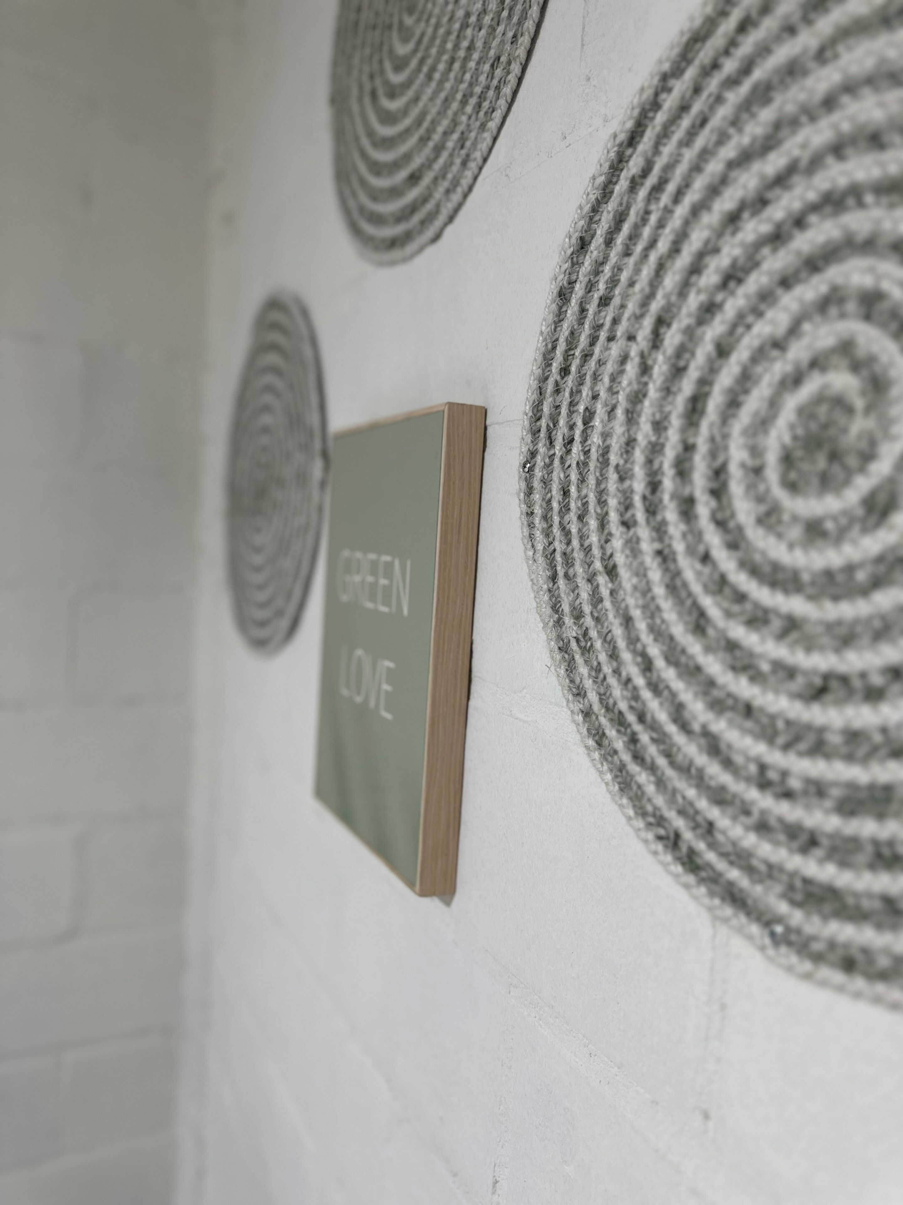 Pared con tres adornos circulares y un cartel enmarcado que dice 'GREEN LOVE'.