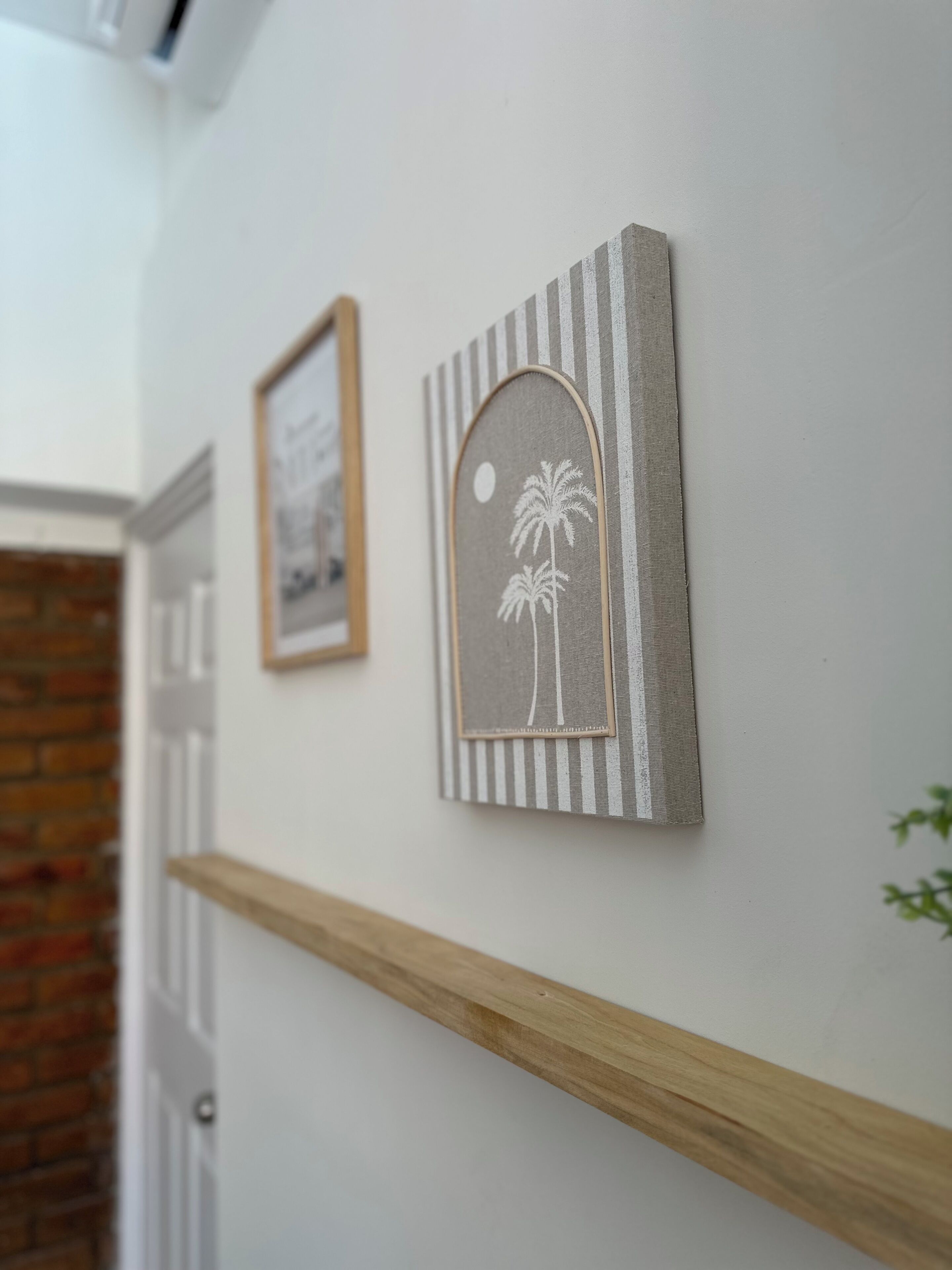 A hallway with a wooden shelf and two framed pictures on the wall.