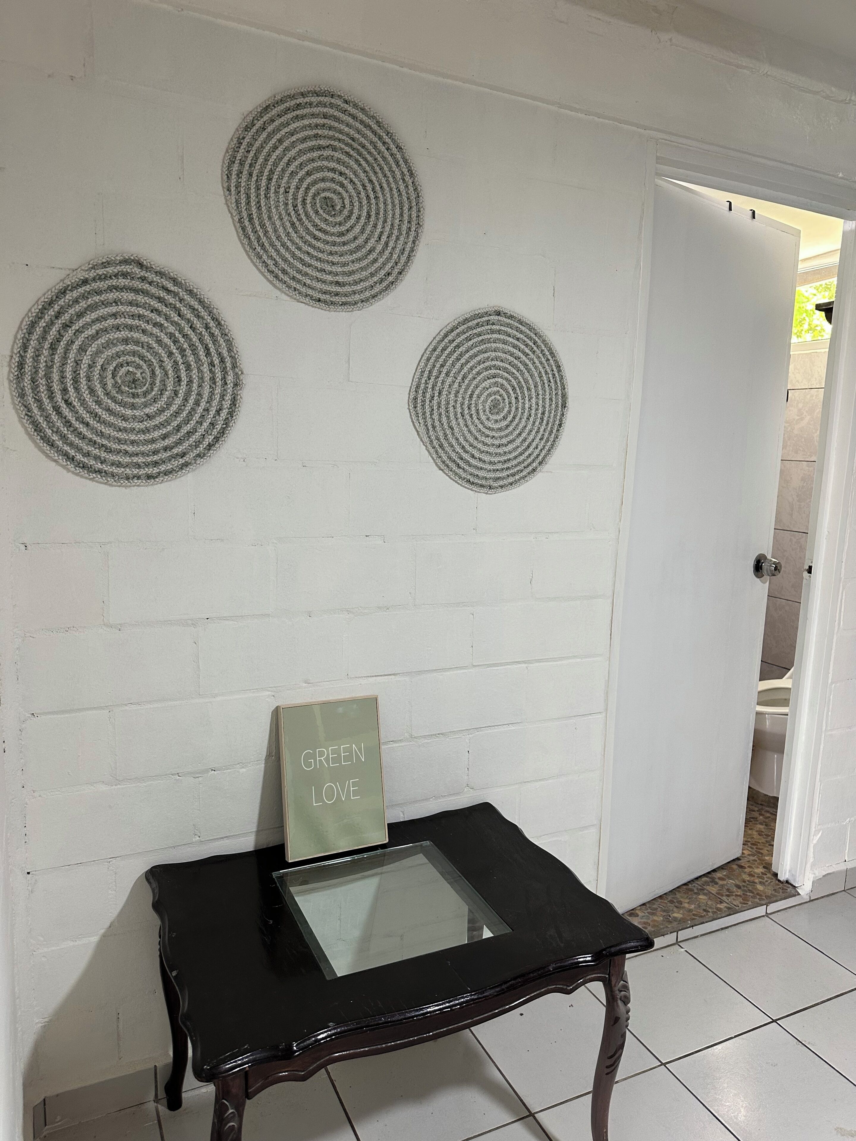 Una habitación con pared de ladrillo blanco, una mesa con cubierta de vidrio y tres adornos circulares en la pared.