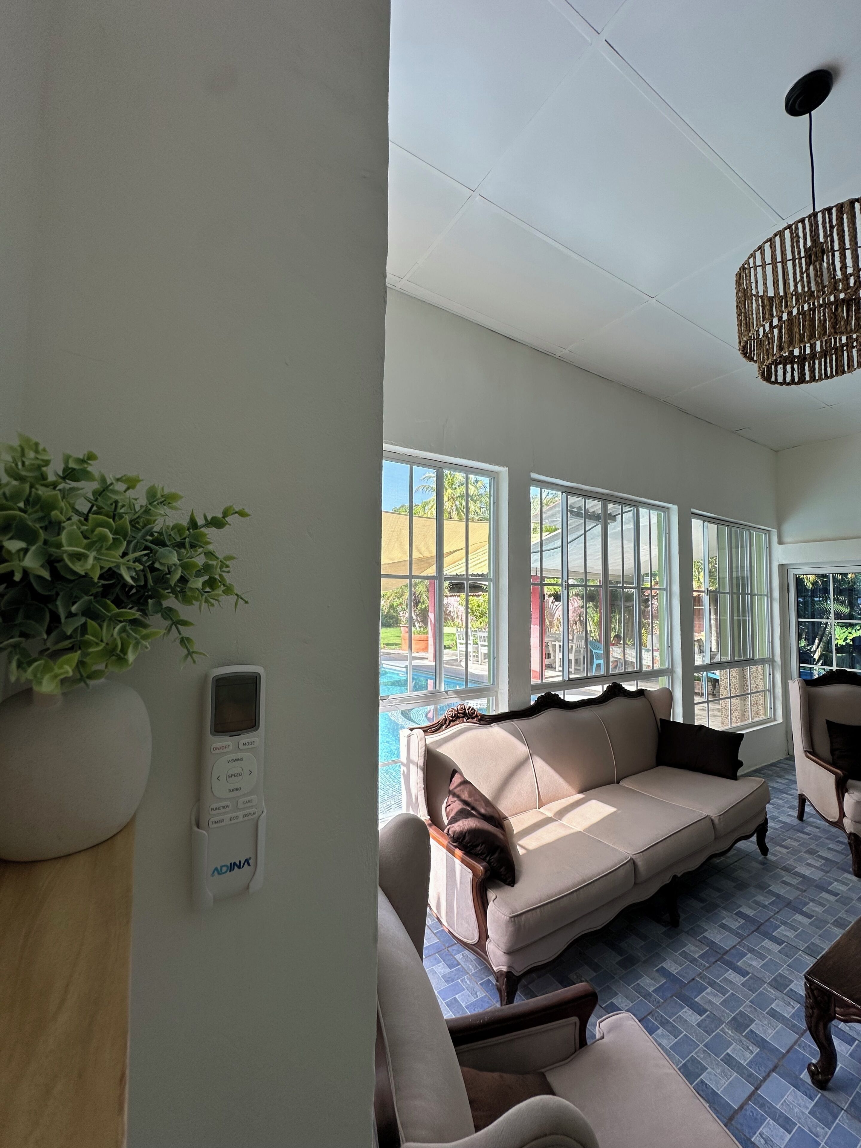 A spacious living area with a large window, a sofa, a chair, and a potted plant.
