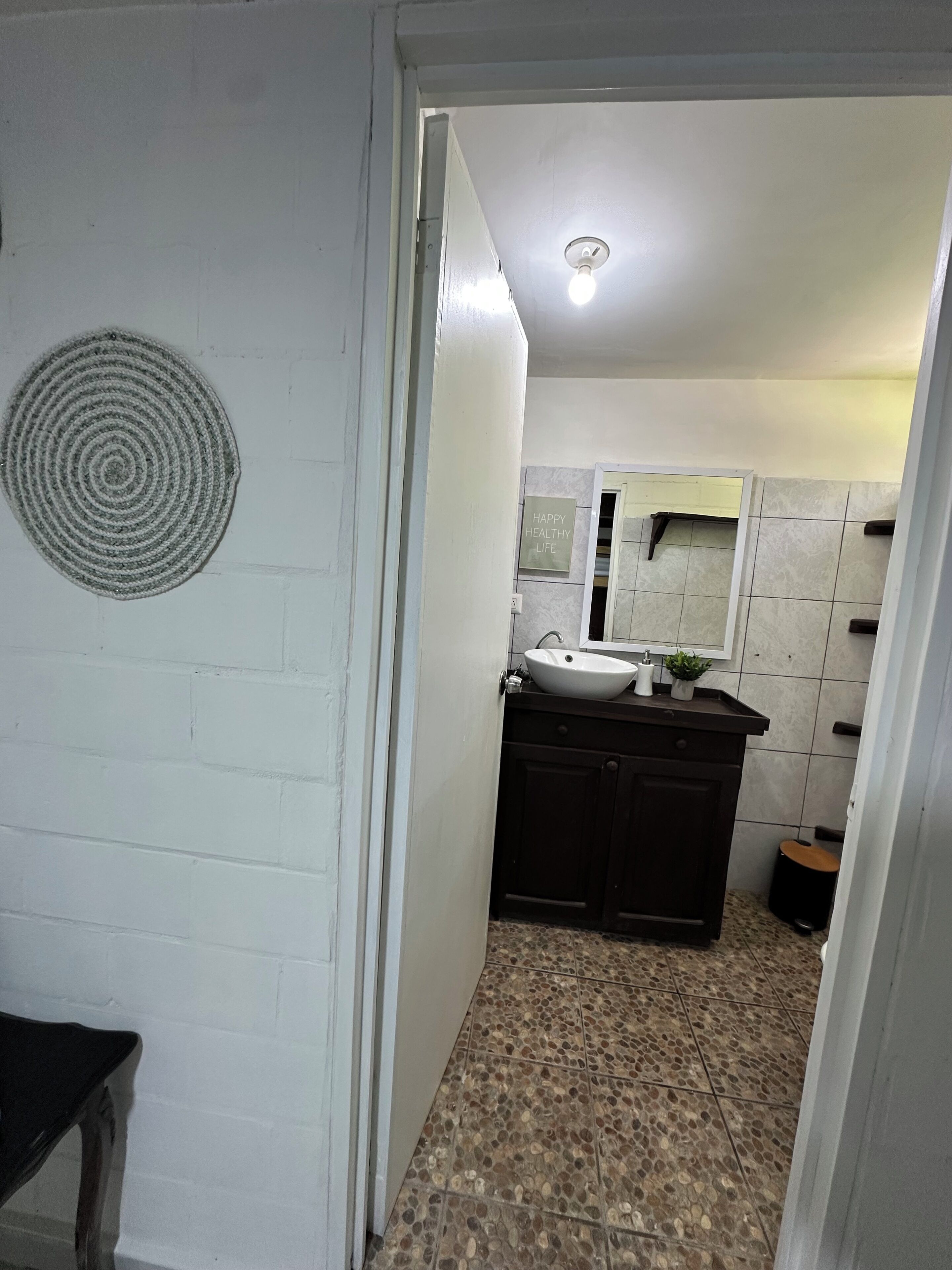 A bathroom with a white sink, dark cabinets, a mirror, and a textured floor.