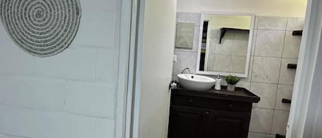 A bathroom with a white sink, dark cabinets, a mirror, and a textured floor.