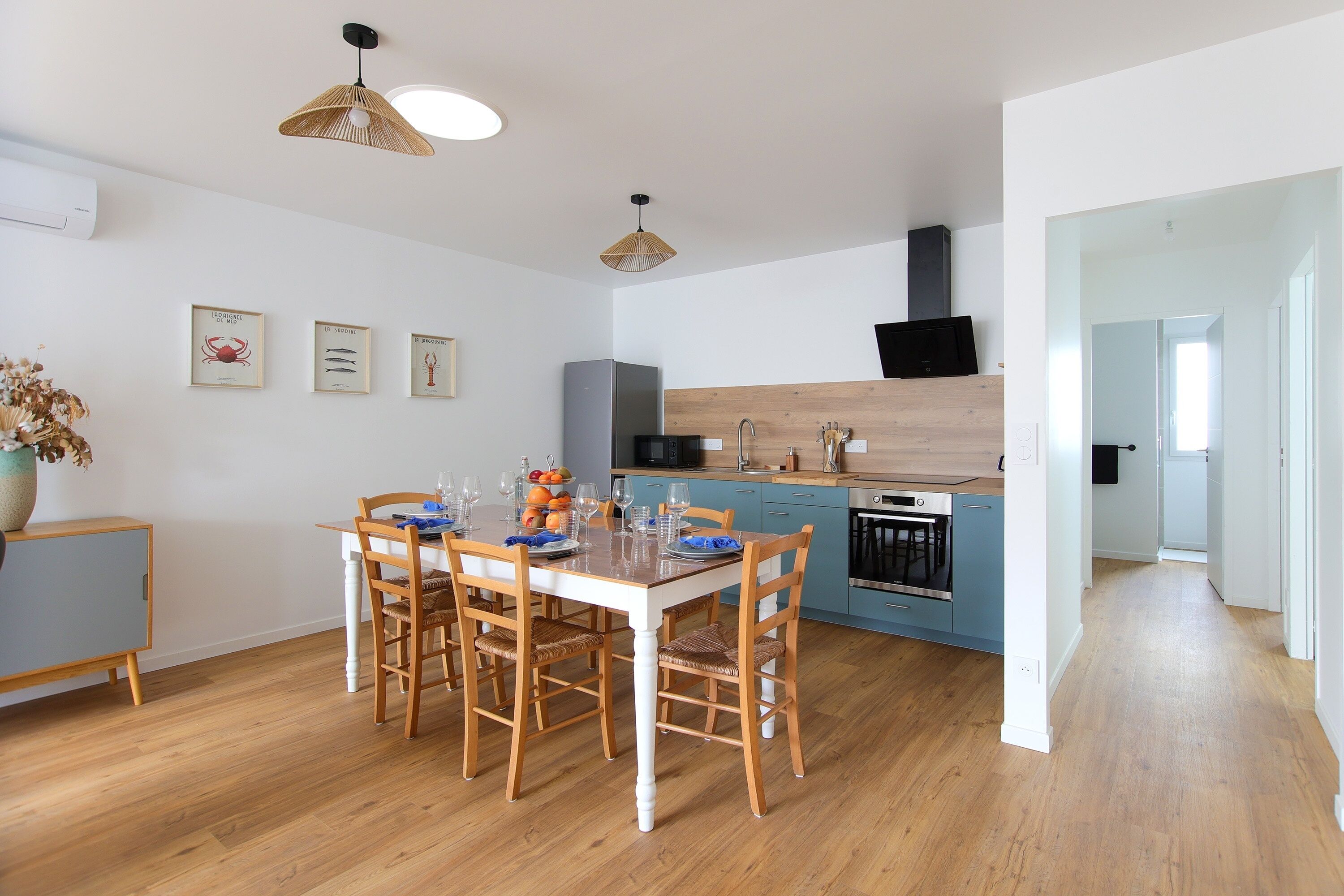Una cocina moderna con armarios de madera, una mesa de comedor para cuatro personas y un horno a la vista.