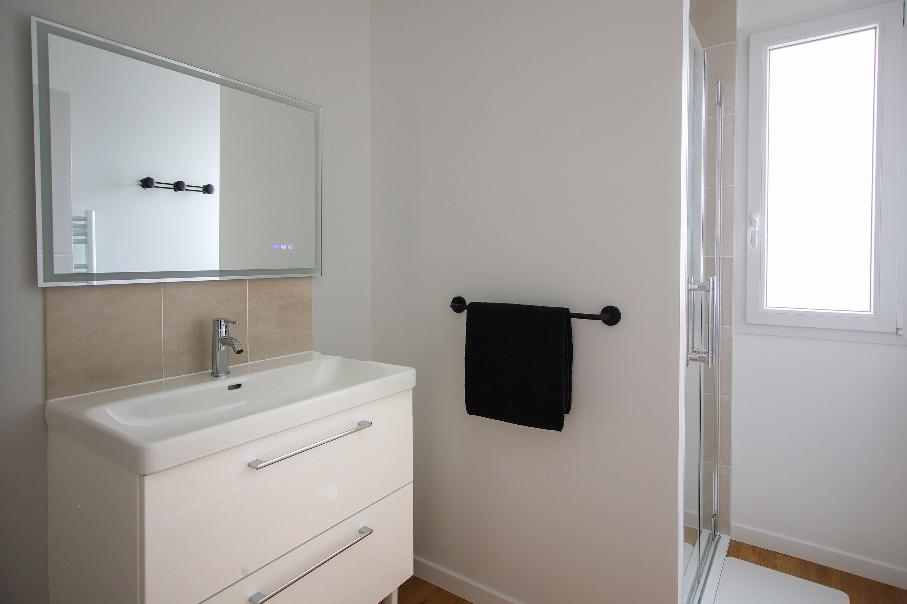 A bathroom with a white sink, mirror, and towel rack.
