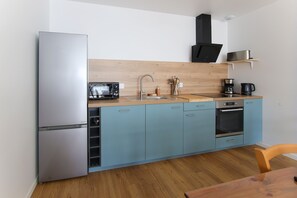 Eine kleine Küche mit Kühlschrank, Mikrowelle, Spüle und Backofen.