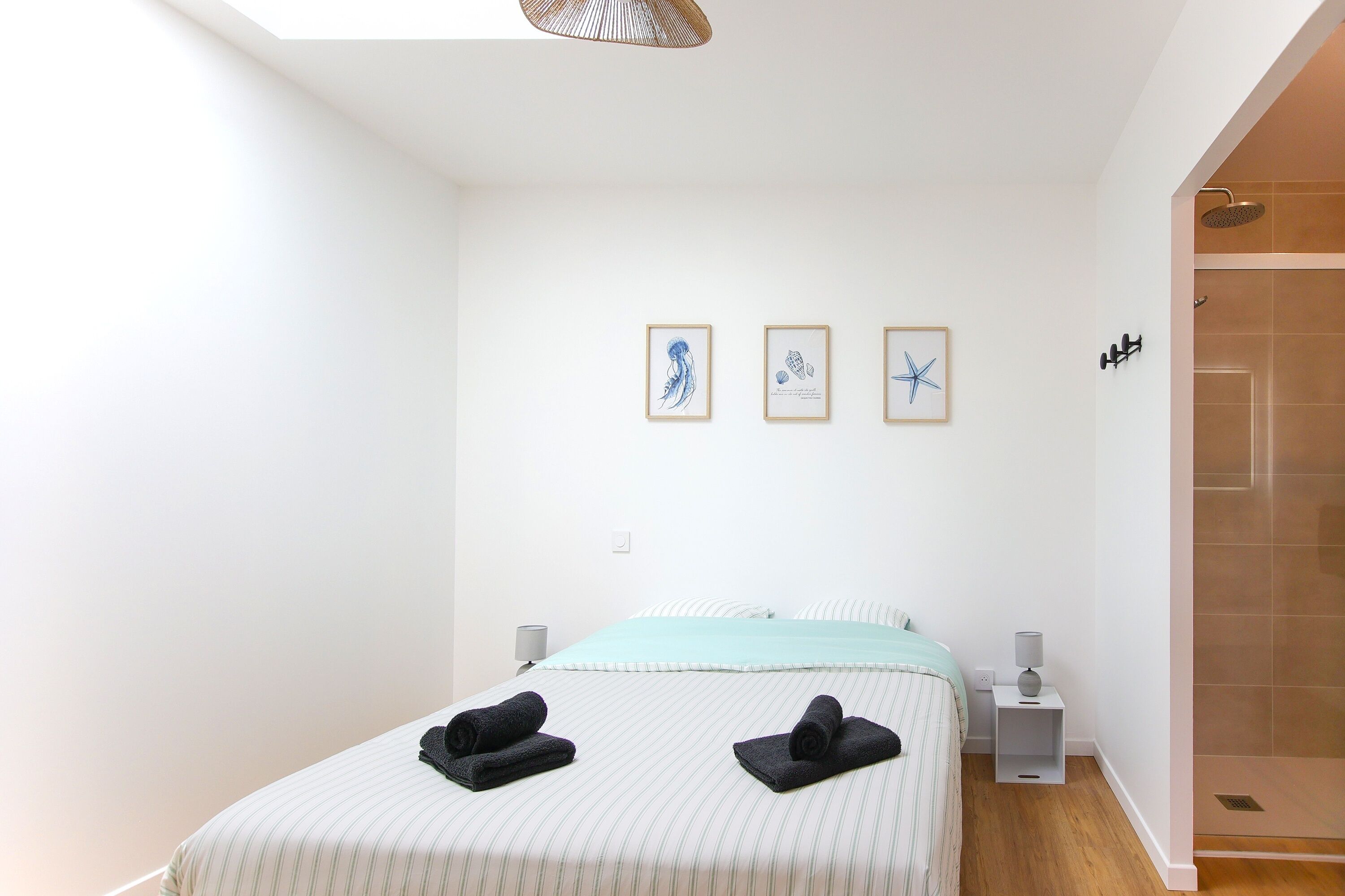 Ein Schlafzimmer mit einem Bett, zwei Nachttischen, einer Wandleuchte und einem Duschbereich.