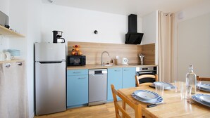 Una cucina compatta con frigorifero, lavastoviglie, forno a microonde e mobili in legno.