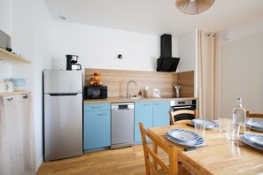 Eine kleine Küche mit Kühlschrank, Geschirrspüler, Mikrowelle und Holzschränken.
