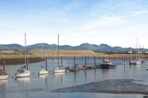 A marina with multiple boats docked, calm water, and mountains in the background. - 2 Bed in Rhydyclafdy (oc-b44972) (Buan)