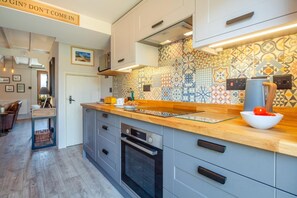 A modern kitchen with a wooden countertop, patterned backsplash, and built-in appliances. - 2 Bed in Rhydyclafdy (oc-b44972) (Buan)