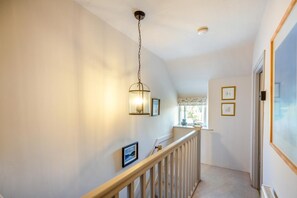 A hallway with a wooden railing, a hanging light fixture, and framed pictures on the walls. - 2 Bed in Rhydyclafdy (oc-b44972) (Buan)