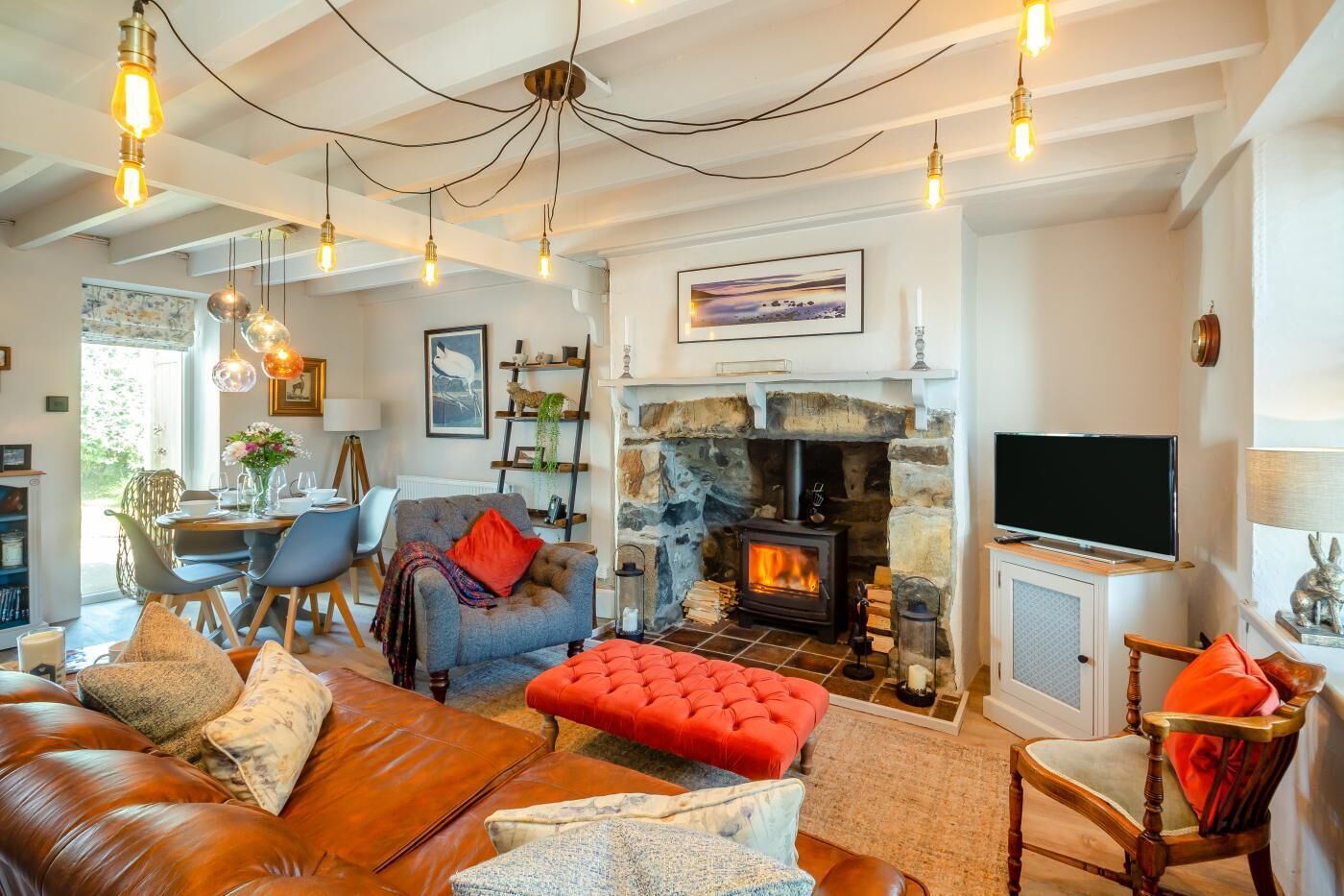 Una sala de estar acogedora con chimenea de piedra, sofás de cuero y un televisor.